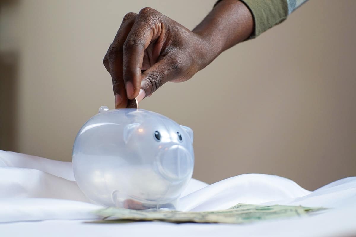 a hand dropping a coin in a piggy bank How to Pay for a Coding Bootcamp