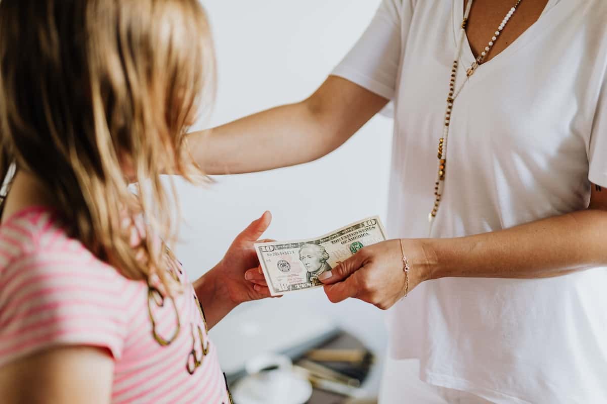 A girl receives a $10 bill from her mom