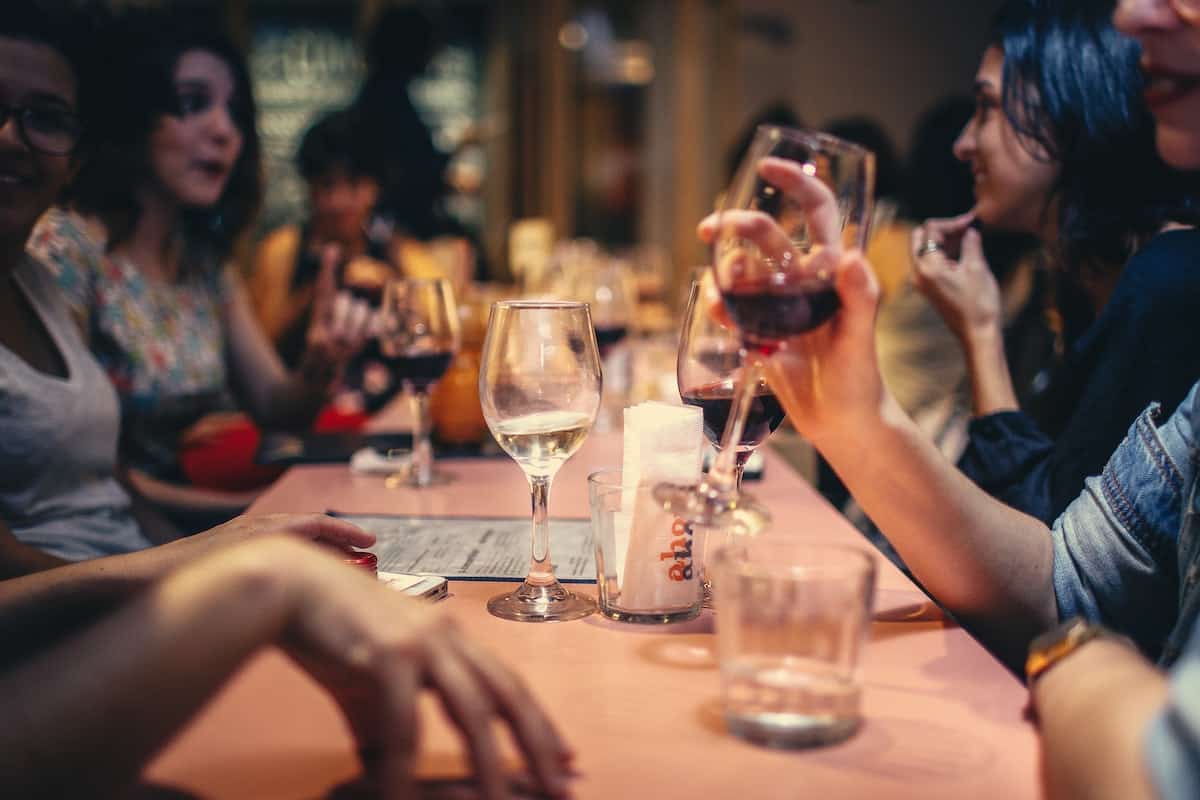 People drinking wine and talking at dining table close up