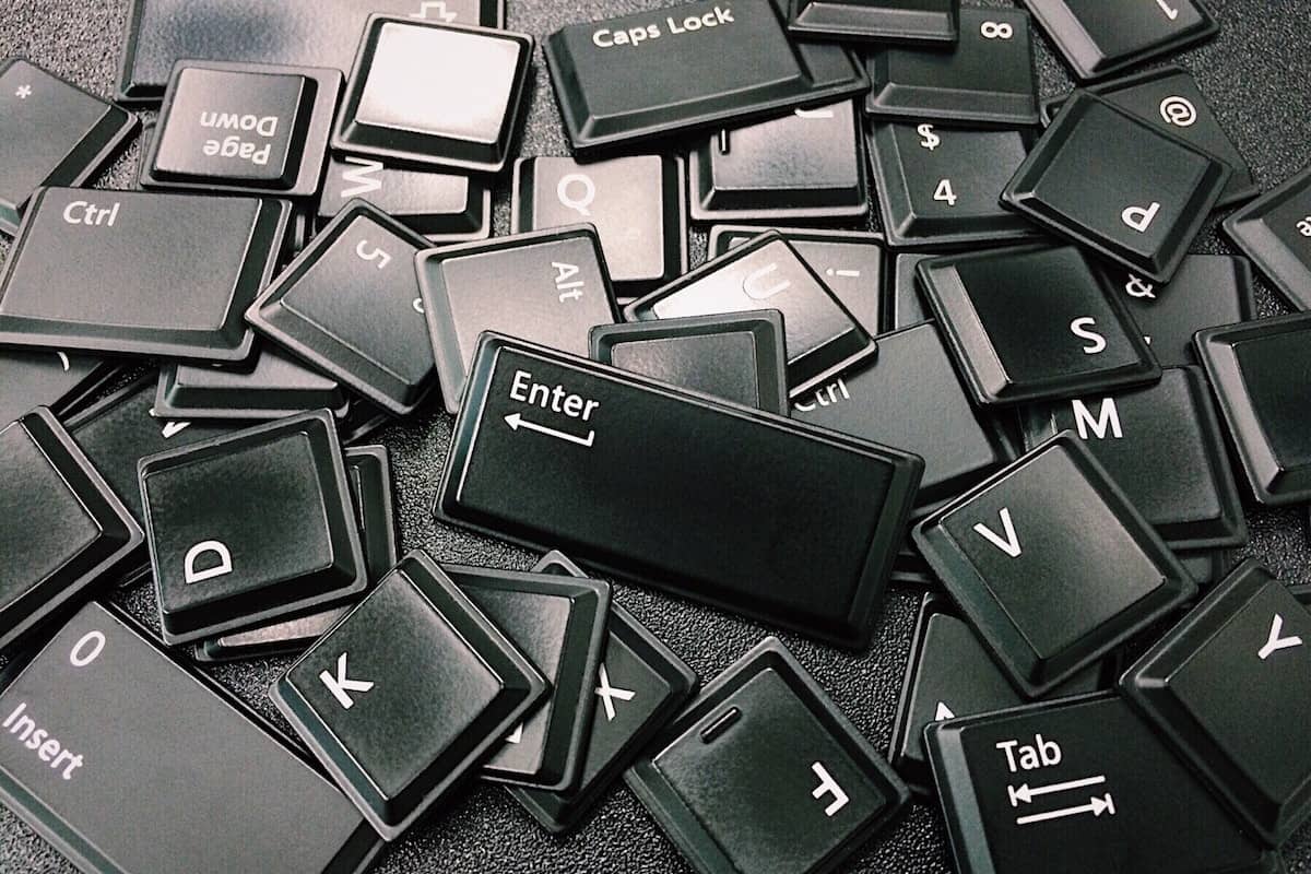 a pile of detached black keyboard keys on a black surface