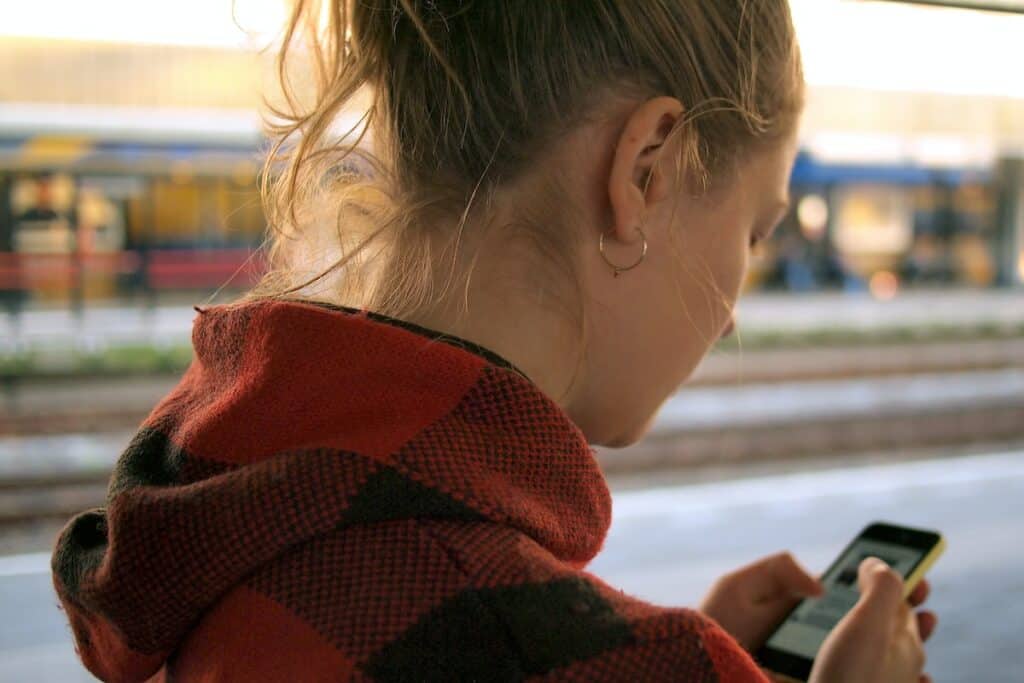 A girl at a train station looking at her smartphone.