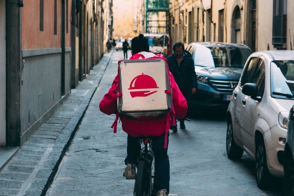 A gig worker earns extra cash by riding a bicycle to deliver items ordered on a food delivery app.