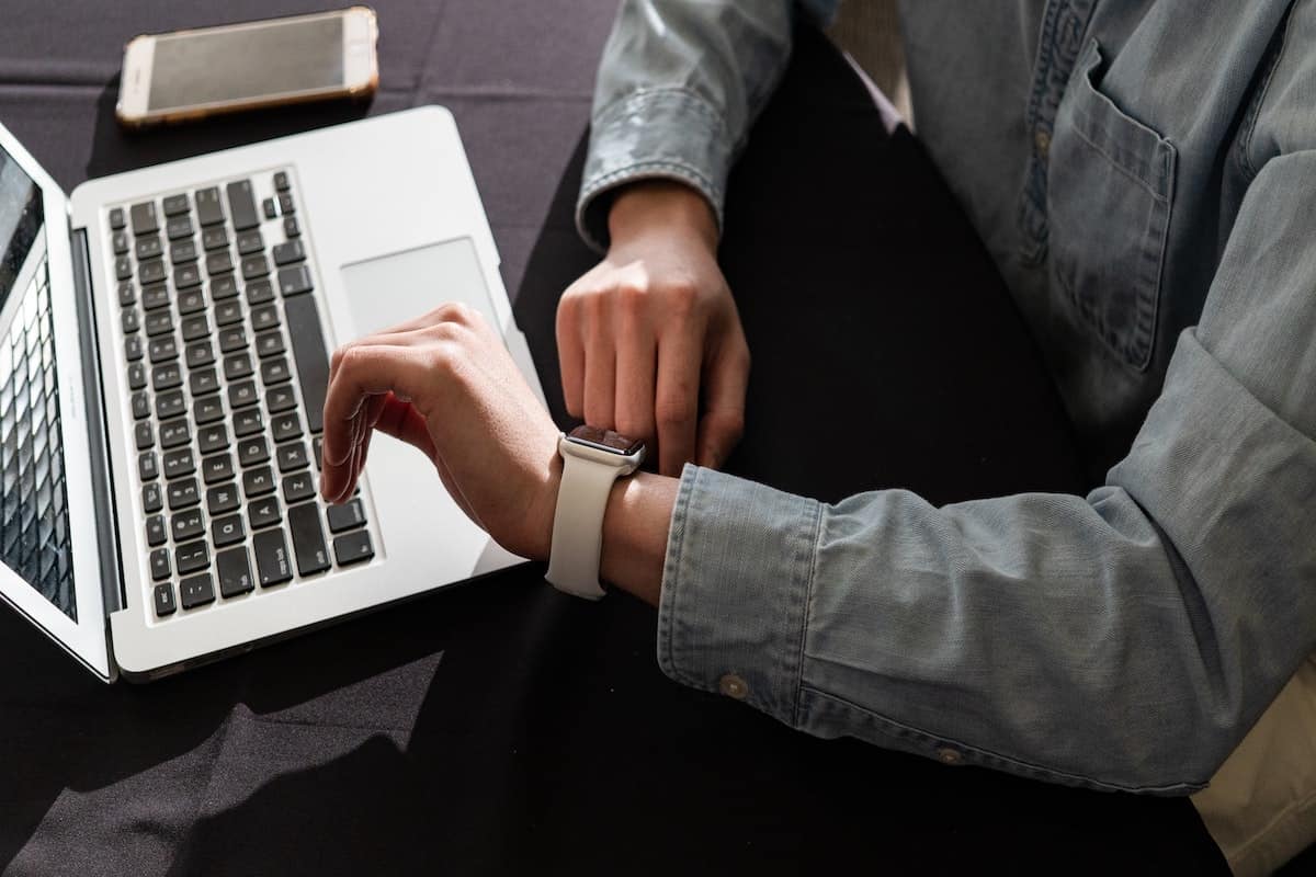 person looking at smartwatch in front of laptop