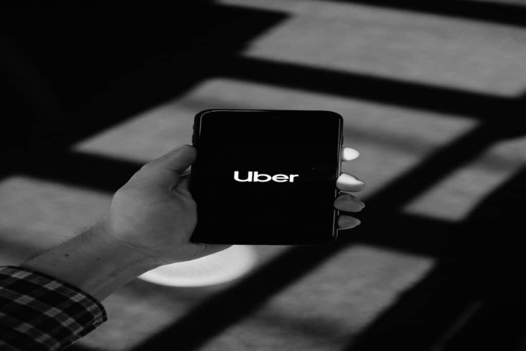 A smartphone being held up by a person’s hand, displaying the Uber application