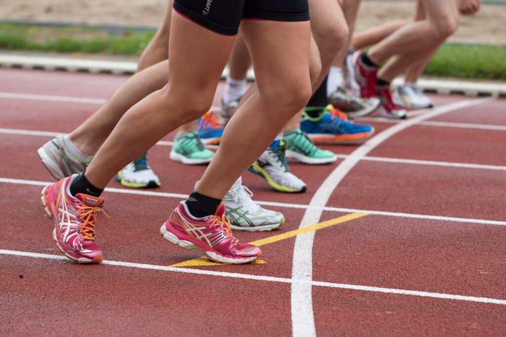 The legs and feet of a group of runners at the starting line of a race.