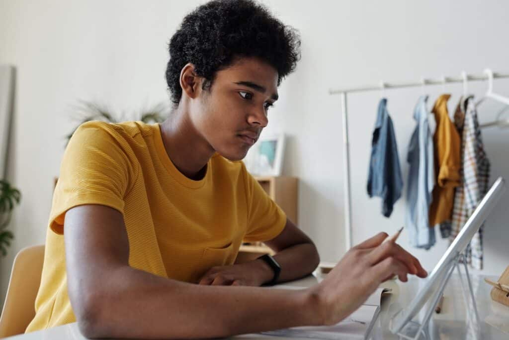 Teenager in a yellow shirt on a tablet with a learning app