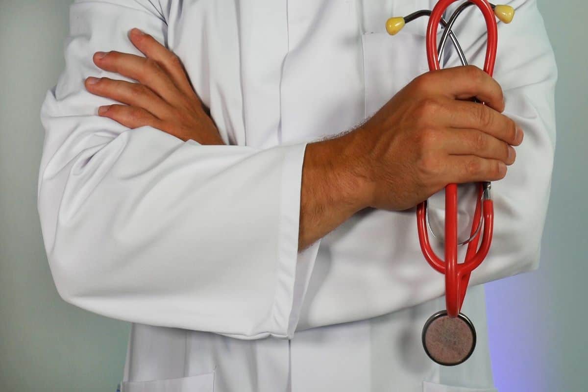 A doctor holding a red and yellow stethoscope while wearing a white lab coat.