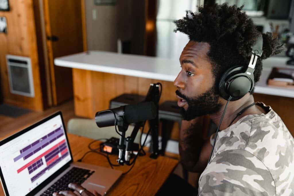 Man recording a podcast with headphones, a microphone, and a laptop.