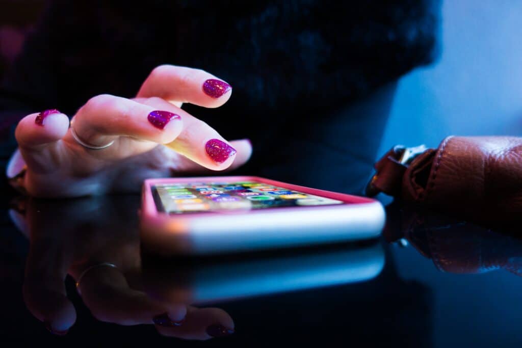 A woman with painted nails taps on an iPhone
