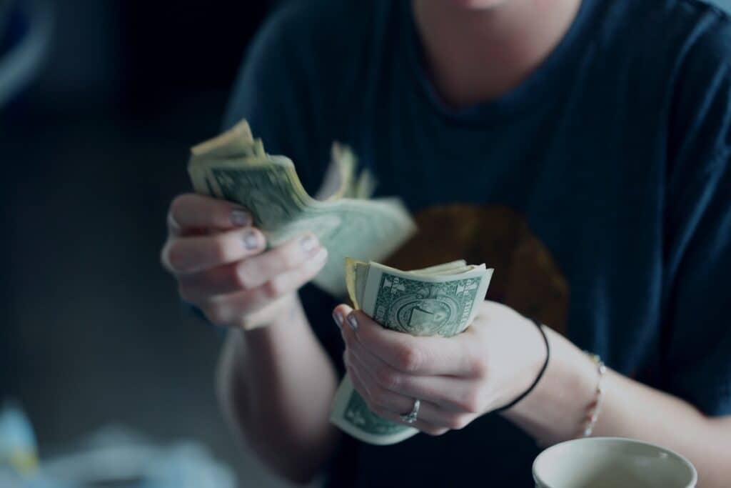 Hands holding and counting dollar bills.
