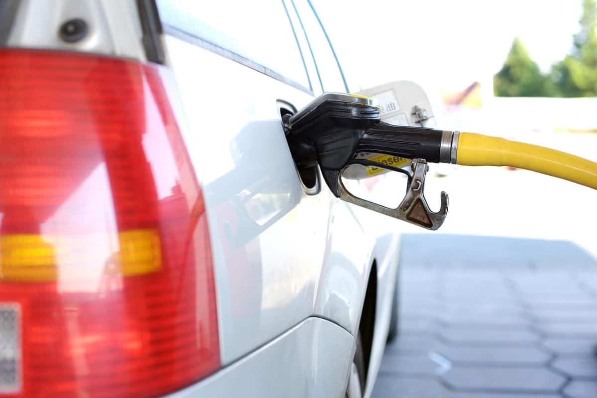 A photo of a refuel gas station pump with a yellow gas pump putting gas into a white car.