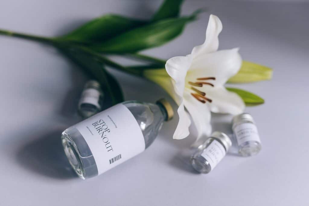 White background, a white lily flower, and bottles that read: Stop Burnout