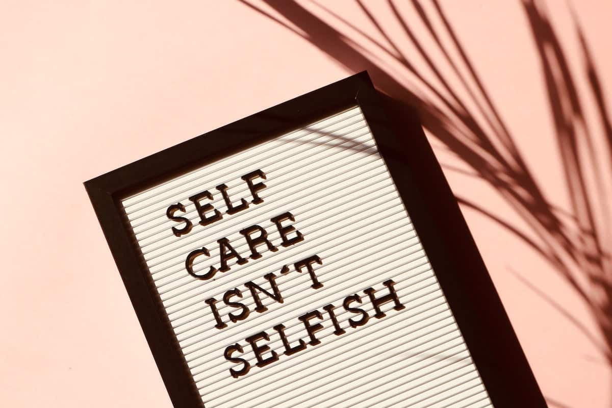 Pink background, black frame with words on white background: Selfcare isn’t selfish