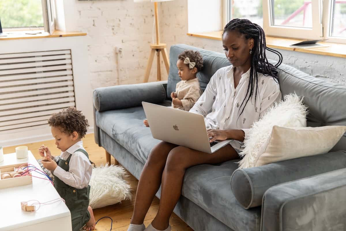 a mom working on laptop with her two kids with her.
