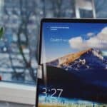 A locked Windows 10 desktop screen on a desk in front of a window.