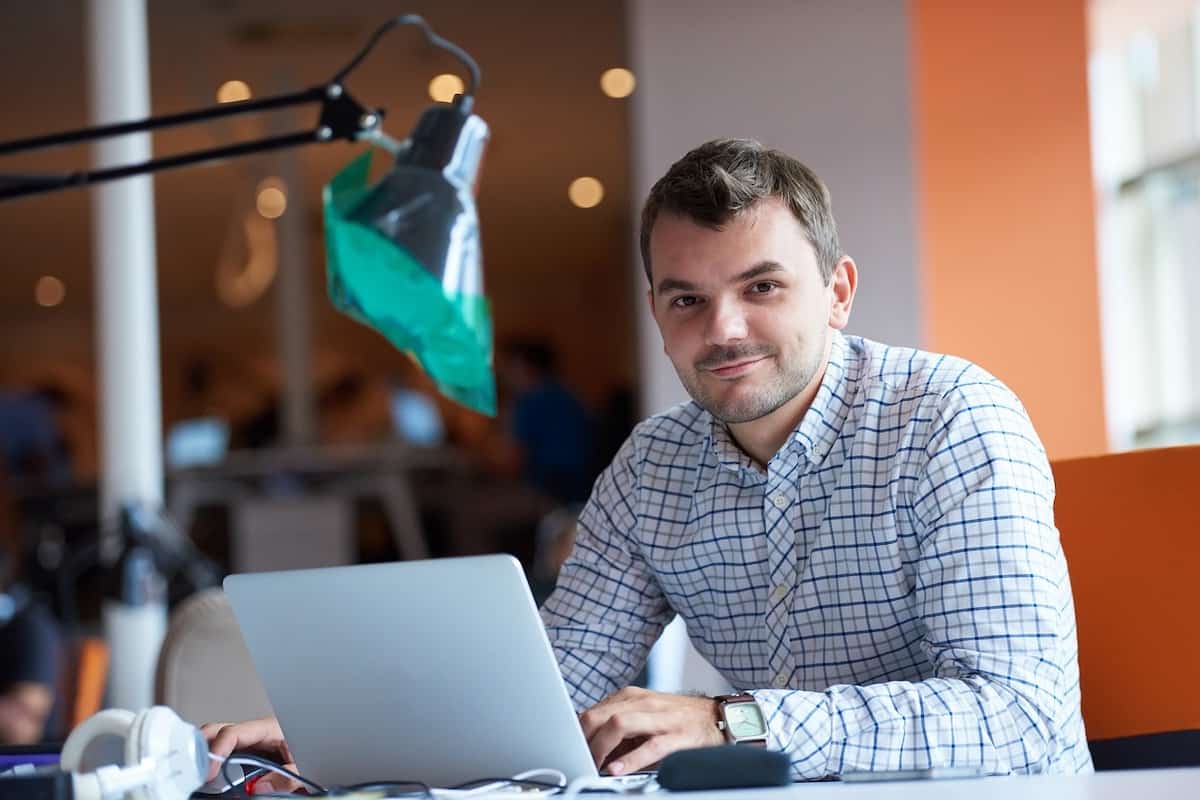 A responsible employee smiling with his laptop open.