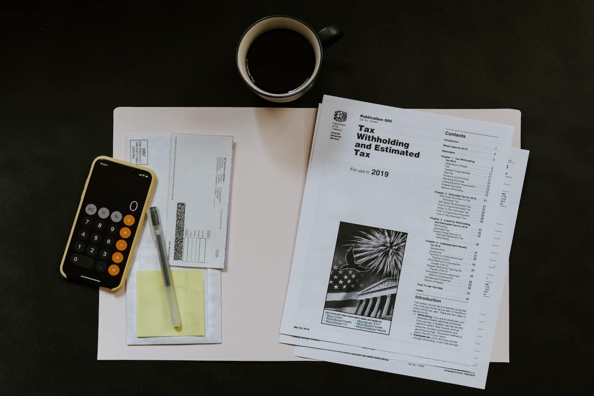Business forms, a calculator and a cup of coffee on desk.